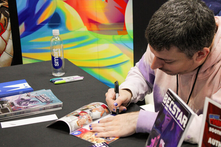 Joe Corallo signing a preview of King Arthur and the Knights of Justice