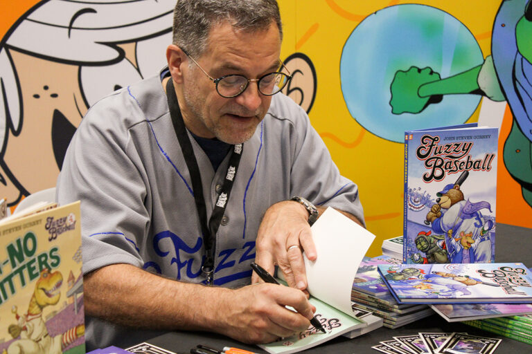 John Steven Gurney, creator of Fuzzy Baseball, signing a copy for a fan at New York Comic Con 2023