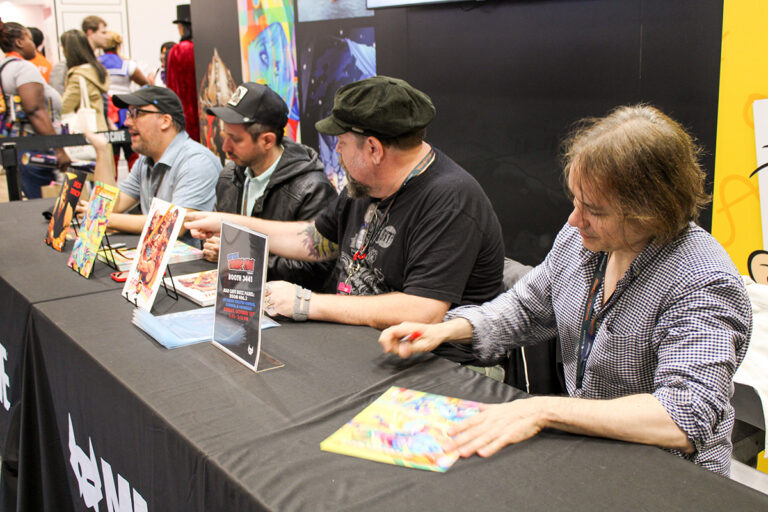 (Left to right) Alex Segura, Steve Orlando, Tommy Lee Edwards, and Chris Batista signing at the Mad Cave Studios booth after announcing their work on Dick Tracy, Gatchaman, and Flash Gordon